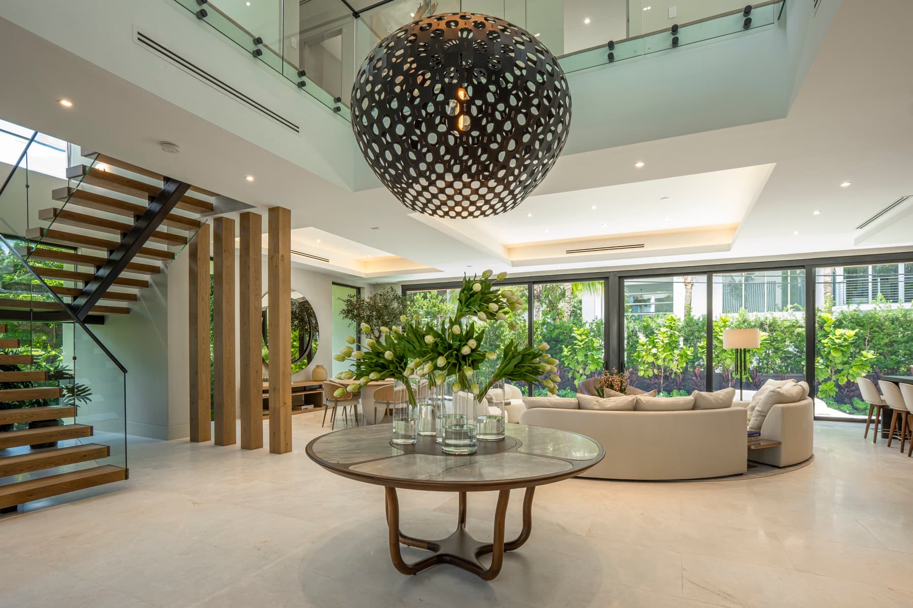 Sala de pé-direito duplo com escada de madeira em balanço e vidro floor-to-ceiling