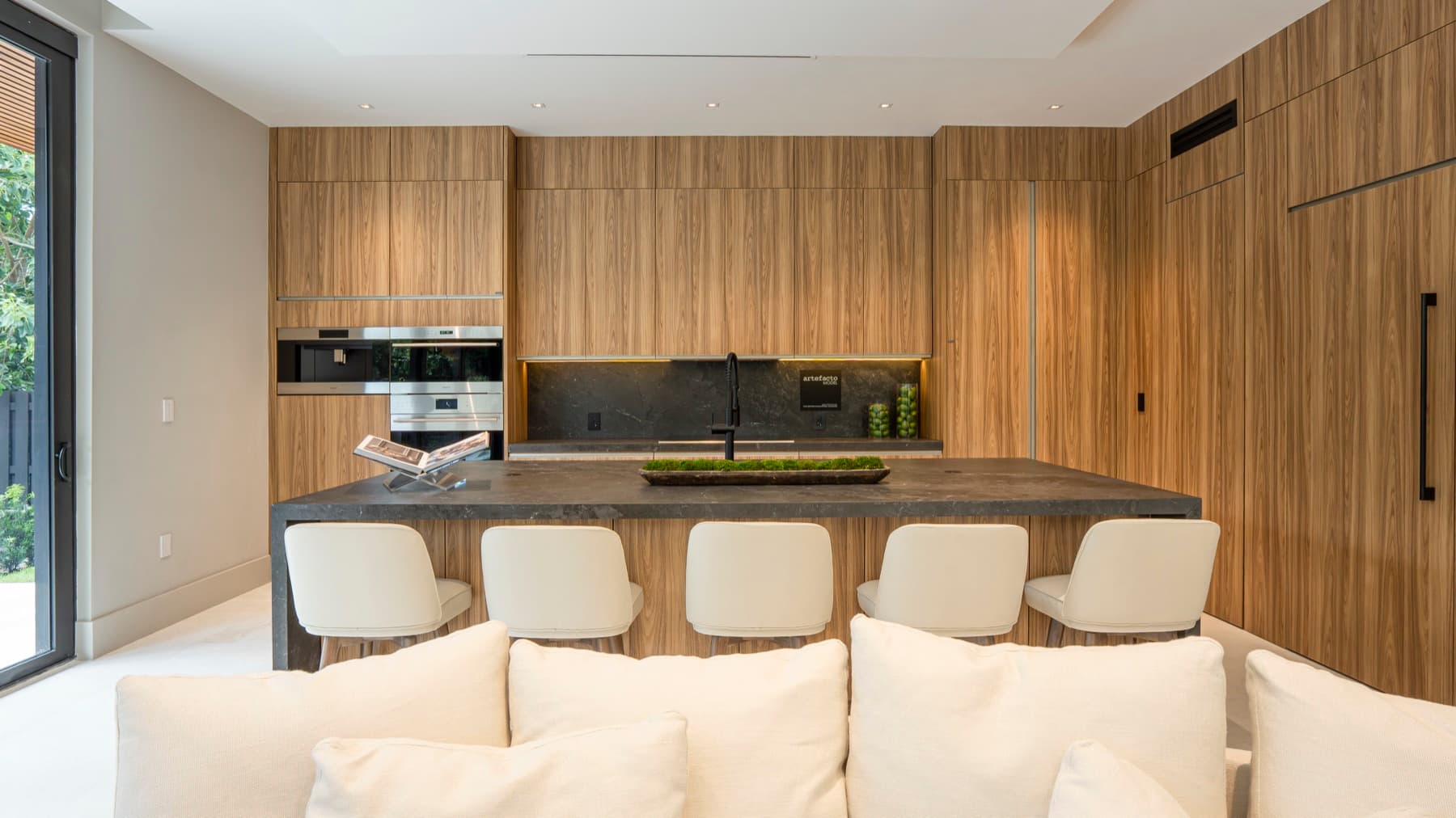 Ilha da cozinha com banquetas cream e marcenaria de madeira floor-to-ceiling