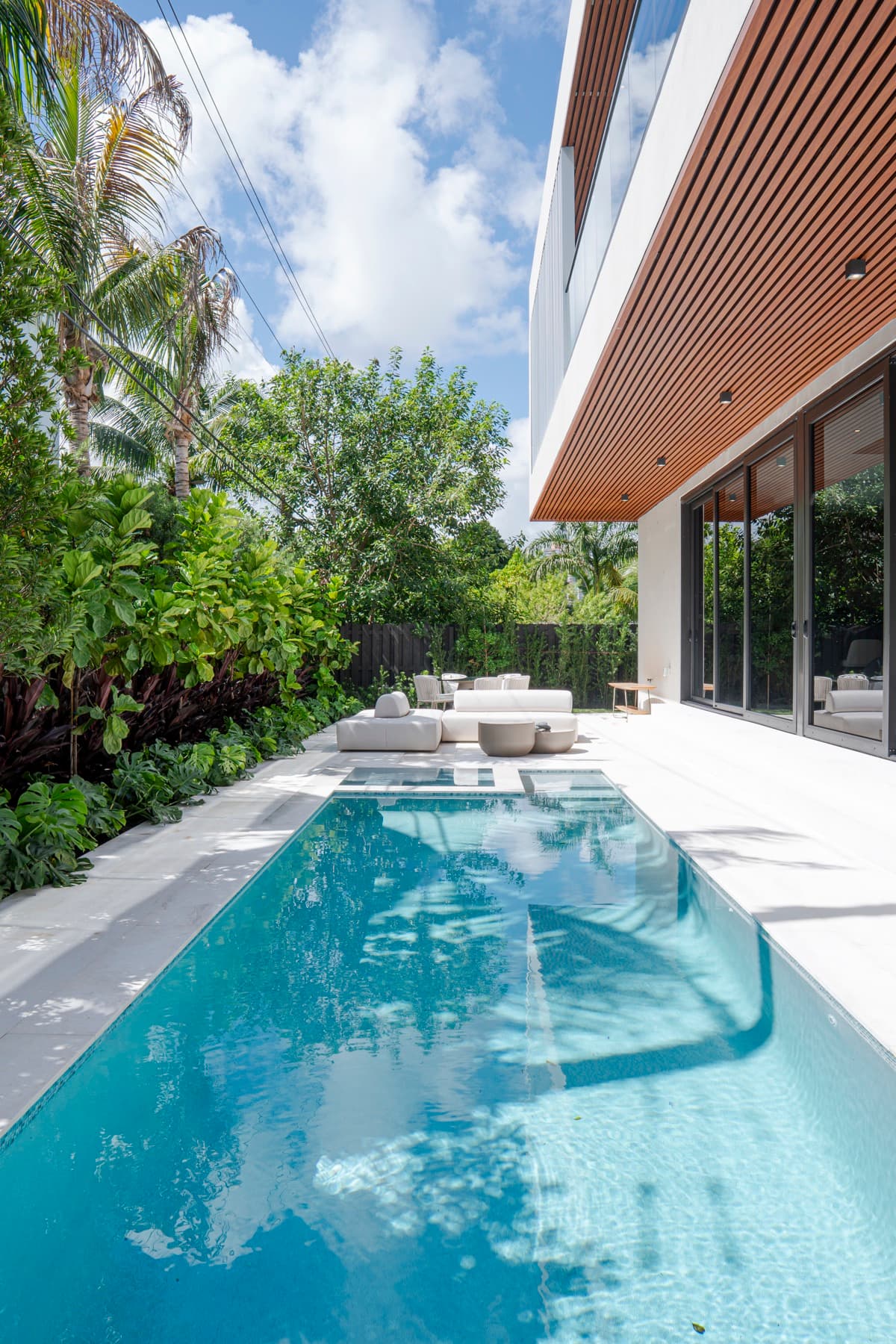 Deck da piscina com estar externo e plantio tropical